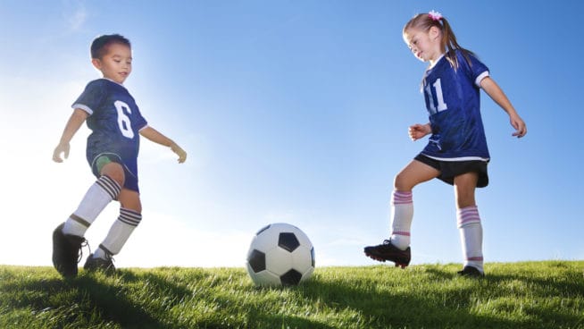 A boy and a girl playing soccer