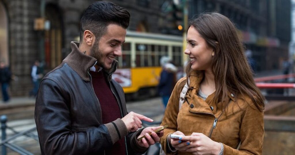 A boy and a girl exchanging phone numbers in the street 