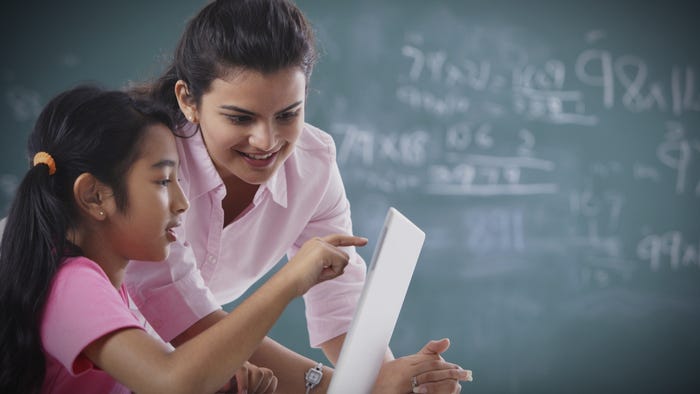 There is a woman teaching a girl using a laptop