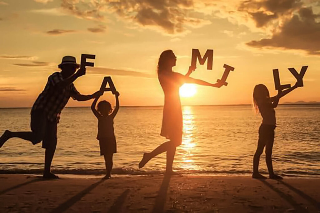 it shows a family two kids and mom and dad at the beach holding letters that read "family"